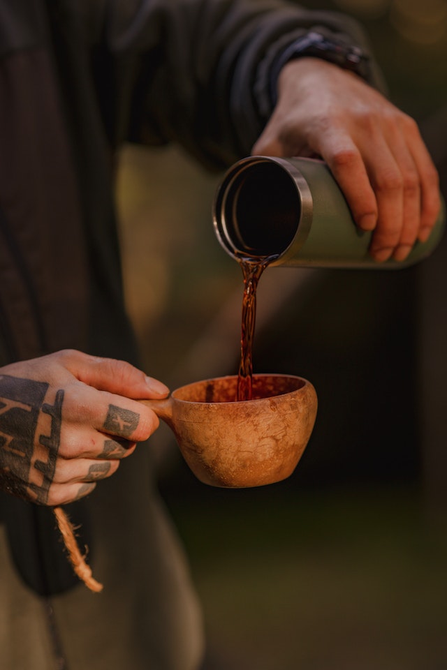 Image de thé noir sur le point d'être servit dans une tasse en bois.